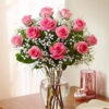 A Dozen Long Stemmed Rose Arrangement In A Glass Urn/Vase With Greenery
