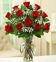 A Dozen Long Stemmed Rose Arrangement In A Glass Urn/Vase With Greenery
